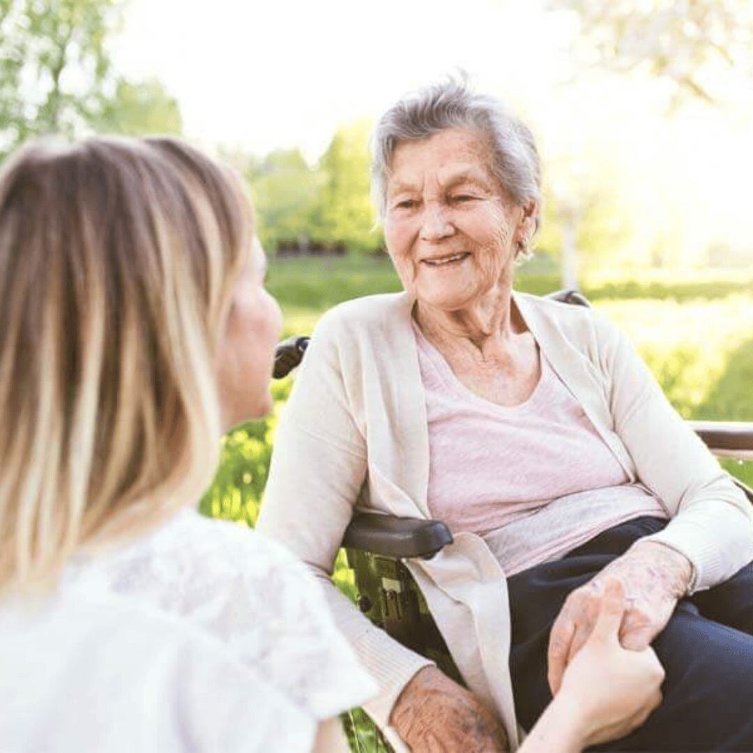 Caregiver holding hands with an elderly woman in the park